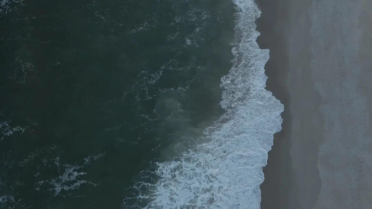 Top Down Aerial View Of Beach With Waves Crashing Into The Sand static slow motion