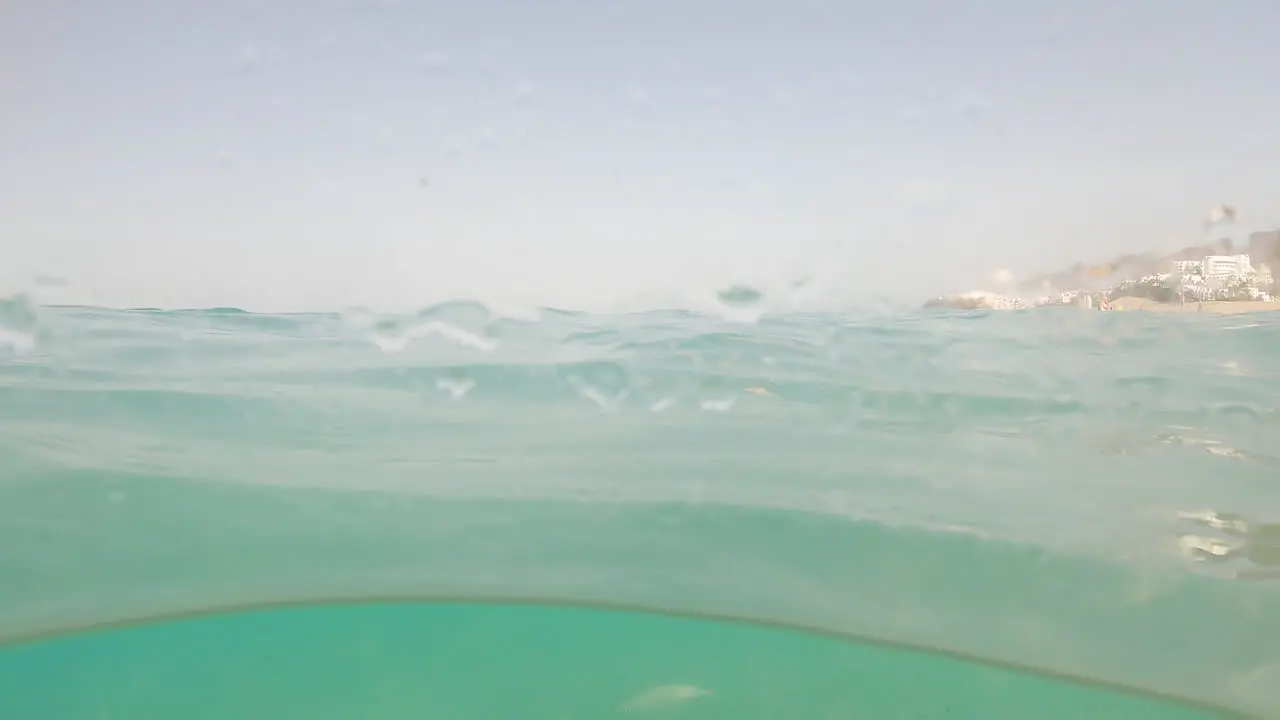 A View Through Wet Camera Lens Of Fishes Swimming Under The Sea Surface In Fuerteventura Spain