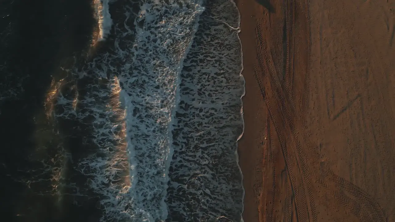 Top view of ocean waves during sunset with one person walking by