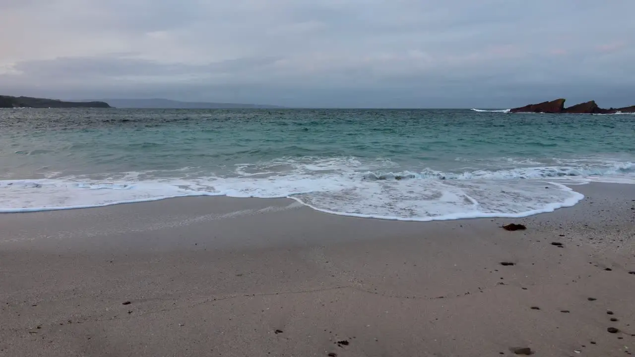 A slow motion shot of waves rolling into a beach in a national park on the south coast of NSW