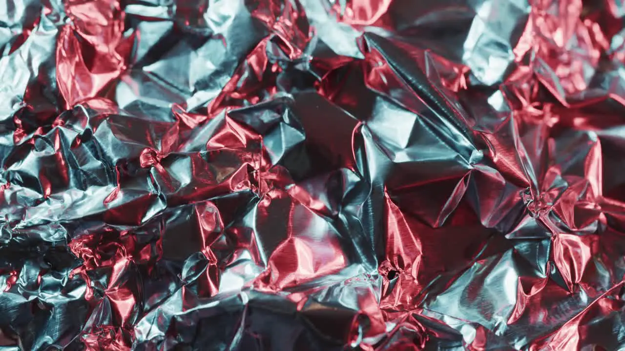 Close up of silver and red crumpled pieces of plastic material in slow motion