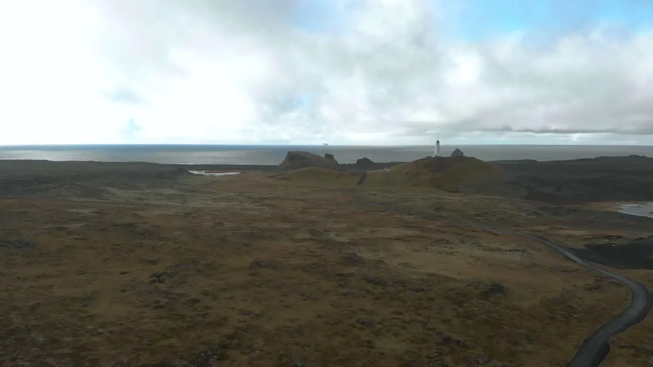 Wide aerial shot of a lighthouse with bleak surrounding coastline