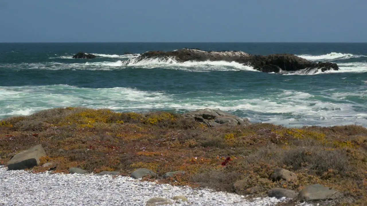 A small offshore island being pounded by waves on the Atlantic coast with a rocky foreground