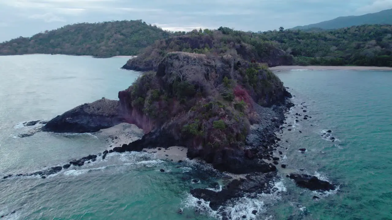 Aerial of waves crashing against headland during a cloudy summer day