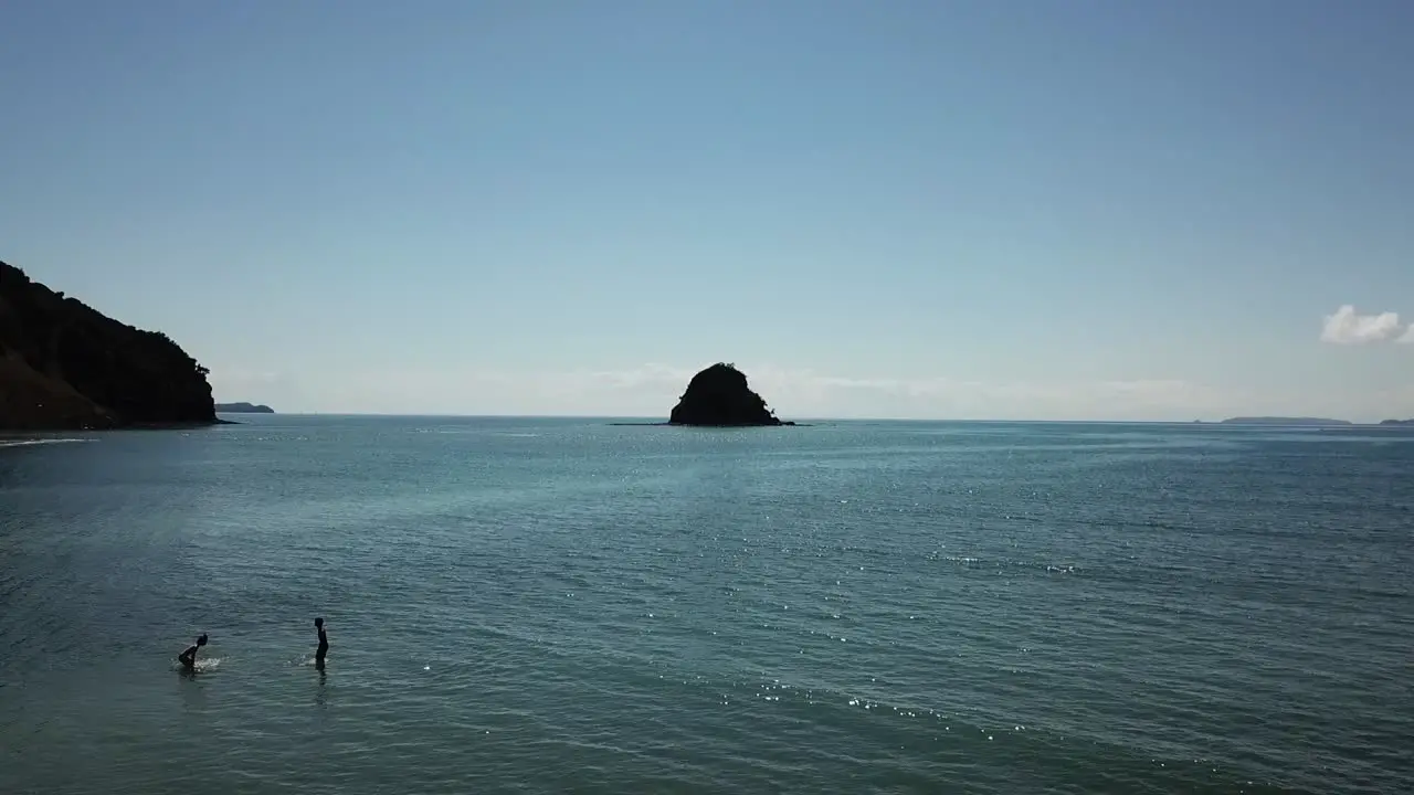 Two people playing in the oceab near an Island in the bay of islands New zealand