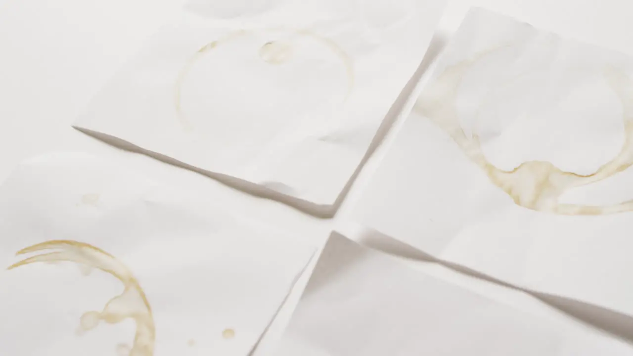 Video close up of four pieces of paper with coffee mug stains on white background