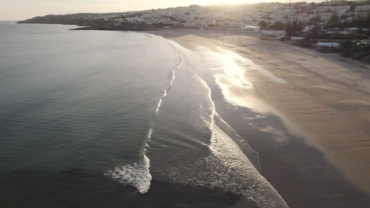 Calm waves roll on shimmering Praia da Luz Shoreline Algarve