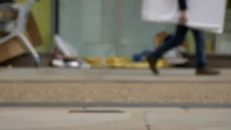 Defocused Long Shot of Feet Walking Past Homeless Persons Belongings In Doorway 03