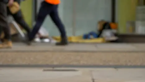 Defocused Long Shot of Feet Walking Past Homeless Persons Belongings In Doorway 04