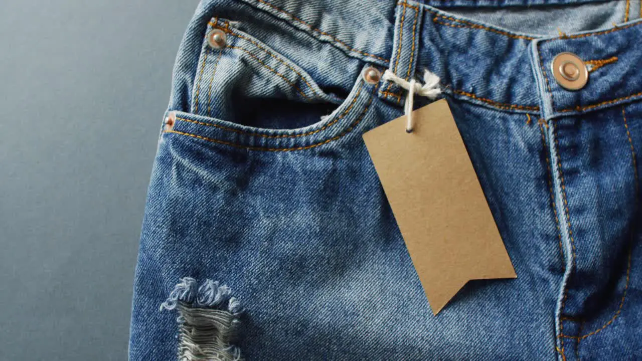 Close up of jeans with tag on grey background with copy space