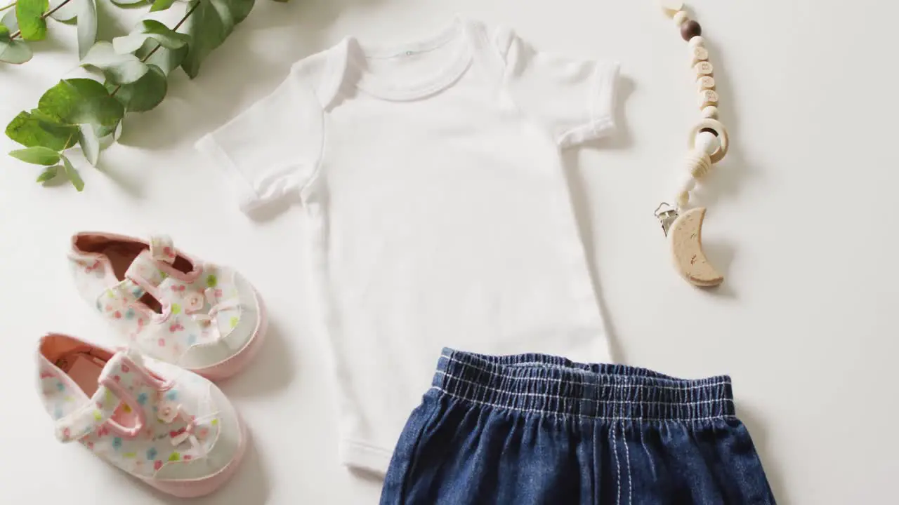 Video of close up of white baby grow shoes and skirt on white background