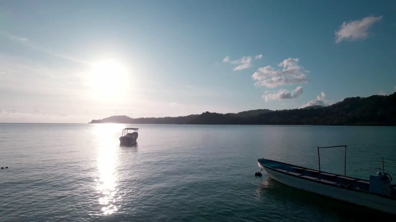 Aerial drone going past 2 boats into the sunset to an island