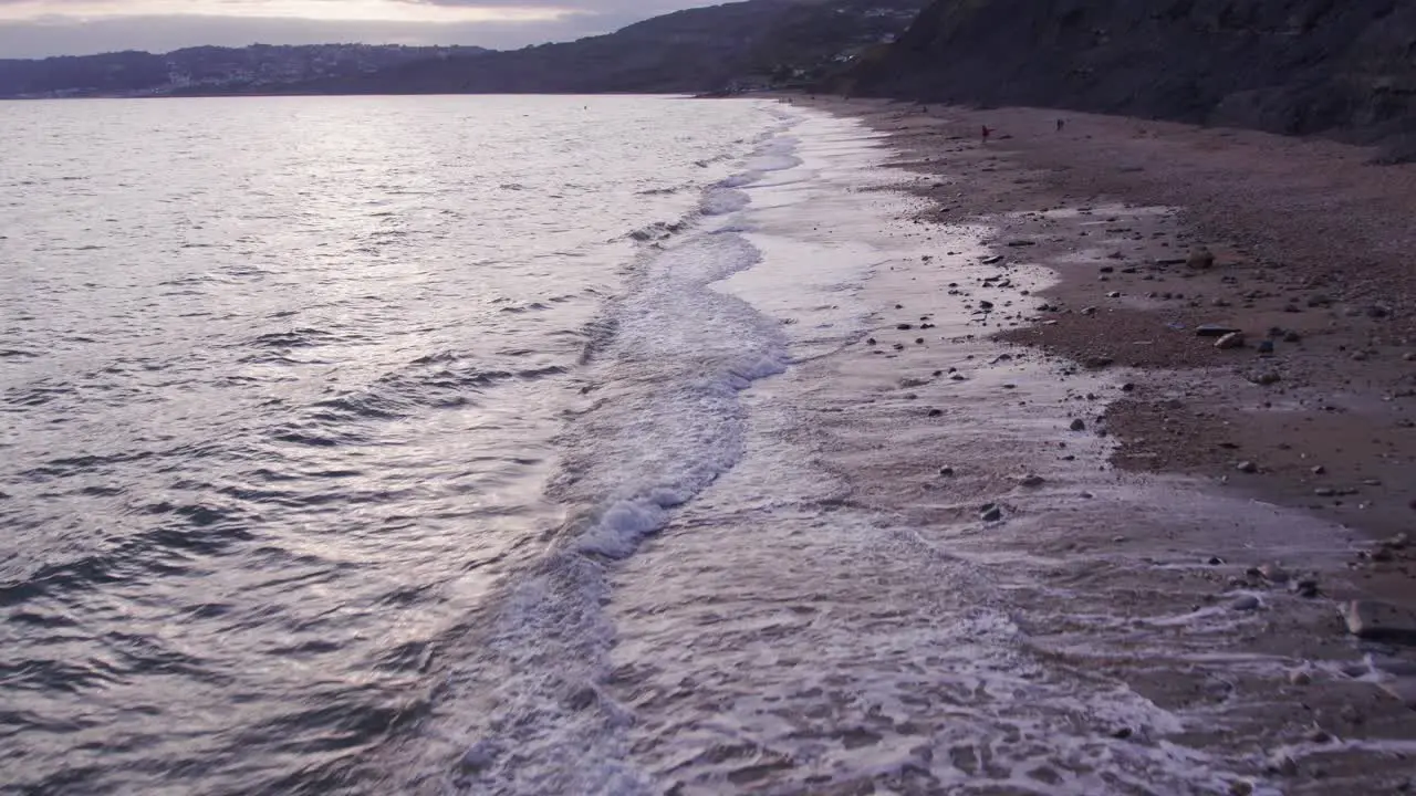 Low slow motion drone shot moving forwards of waves crashing on the beach Jurassic Coast Dorset UK