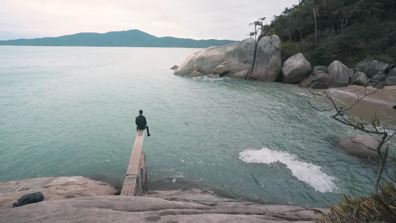 Young man sitting relaxing on a trampoline above the water on a secret brazilian beach