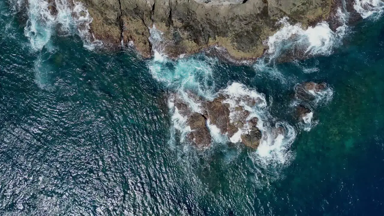 Drone aerial panning view of waves breaking on a rocky coastline