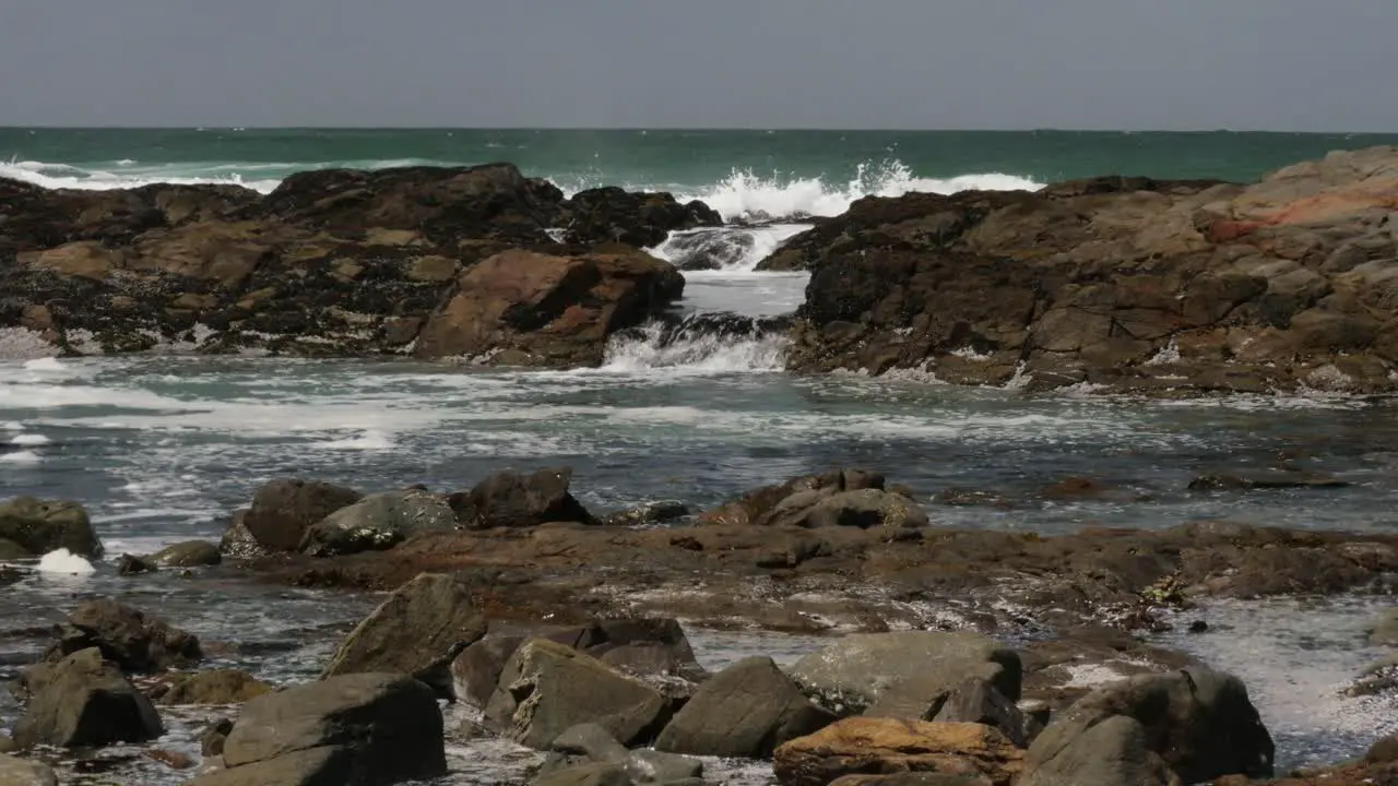 Ocean waves wash over rocks into a pool