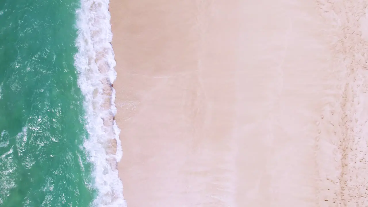 Waves crashing on beach abstract vacation background aerial top down view