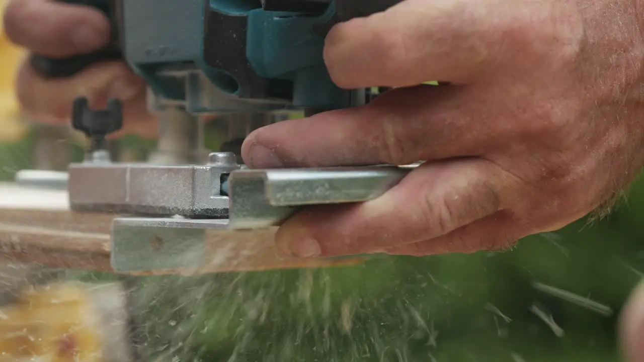 Hands of man working with wood outdoors using electrical machine close up