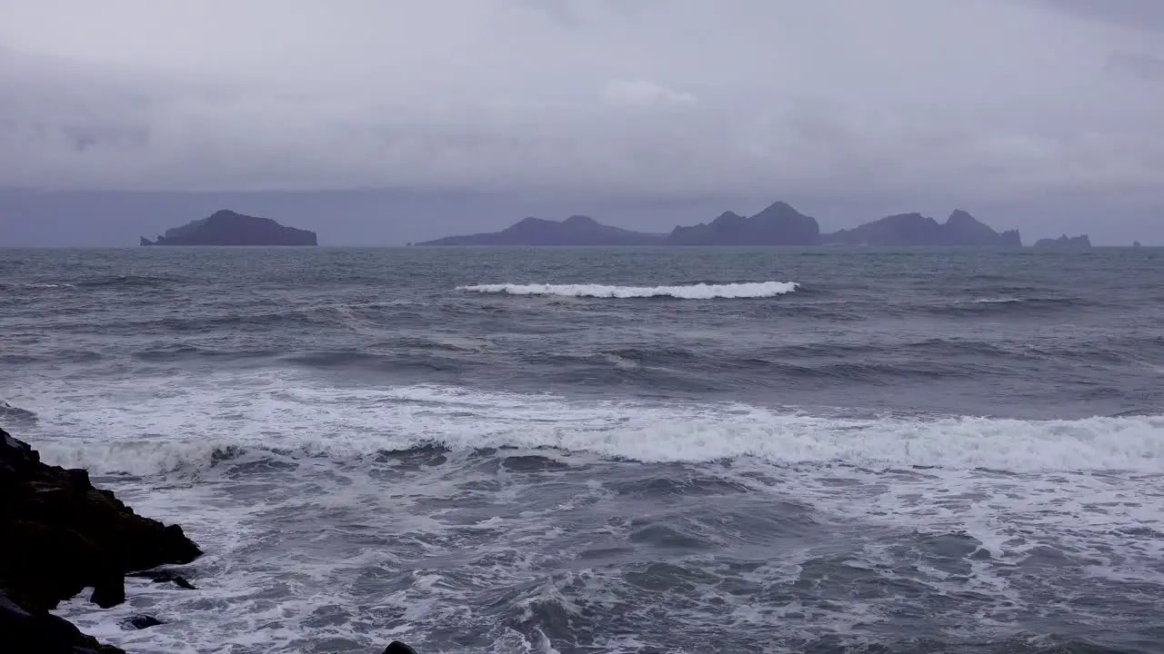 Establishing shot of the Westmann Islands in Iceland with a stormy dark sea foreground