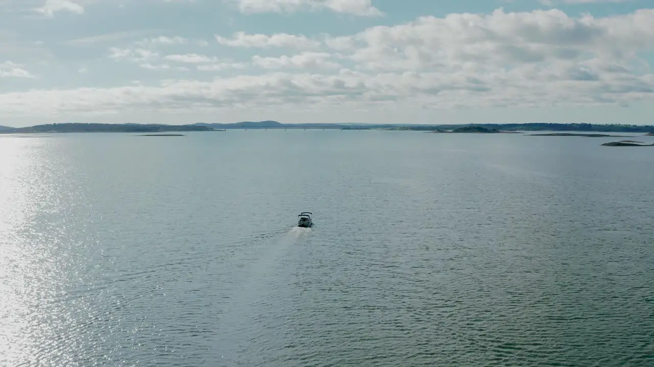 small motorboat sailing in calm open water on sunny summer day aerial view