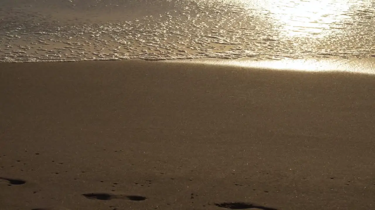 Wave Washing Away Footprint at Sunset