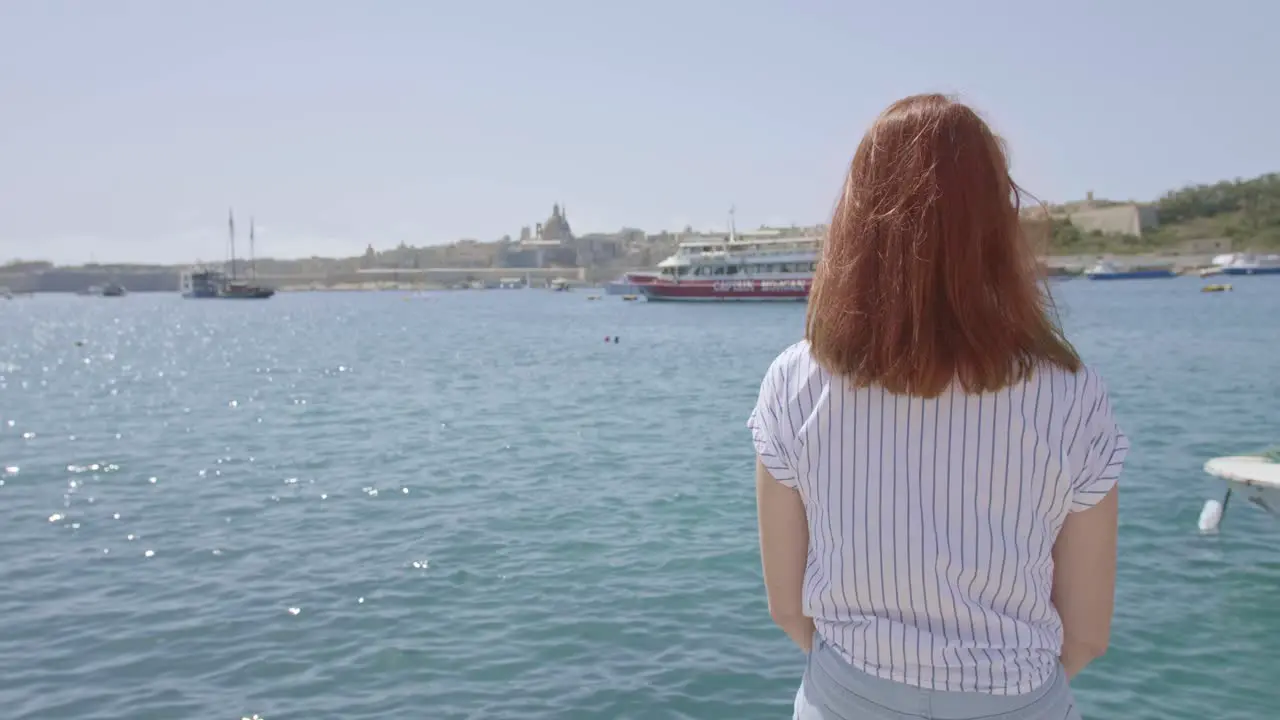 Young woman sitting and watching the boats in the Grand Harbor Valletta Malta