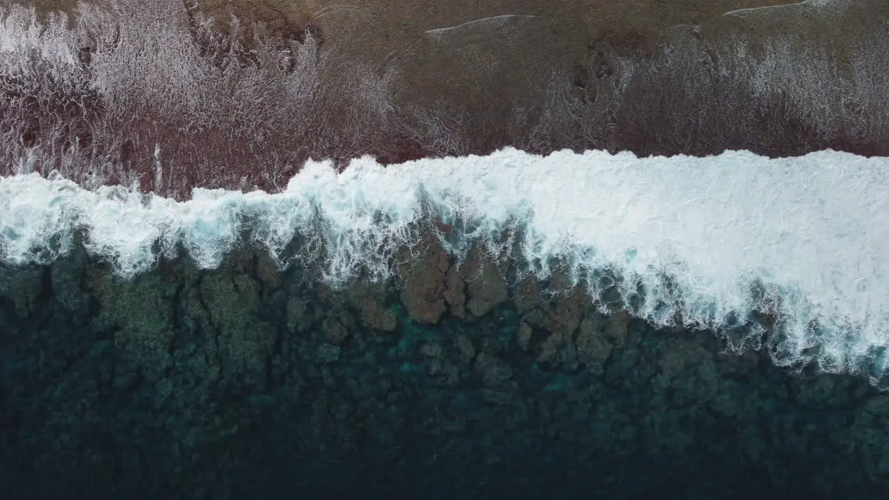 Bird's eye view of ocean waves crashing against shore in Loyalty Islands New Caledonia