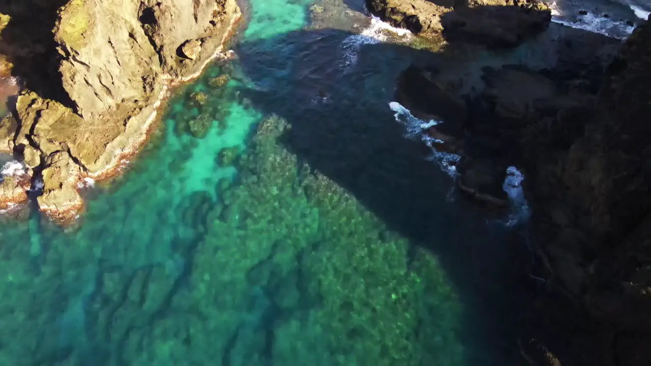 Reveal of crystal blue waters and rocky reef breaking onto seashore of pacific island