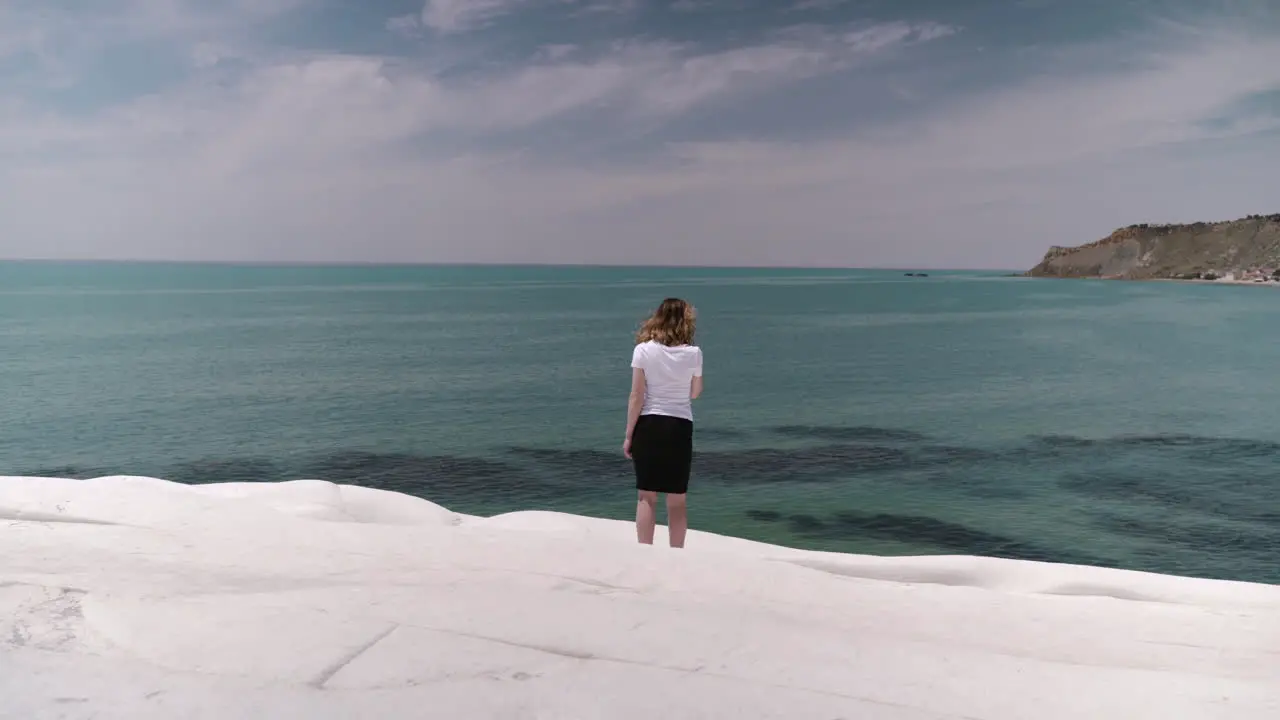 Woman standing on white cliff Scala dei Turchi by sea coastline in Sicily