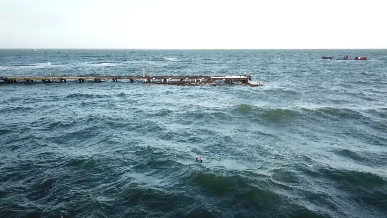 Drone aerial over ocean Melbourne wavy windy cloudy man swimming in winter