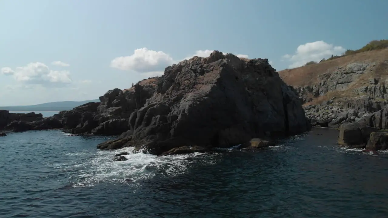 Aerial pan shot around big rocks in the sea sunny summer day-1