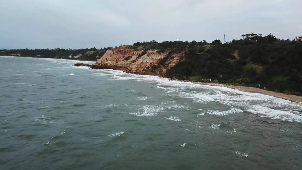 Drone aerial over ocean Melbourne wavy windy cloudy cliff side