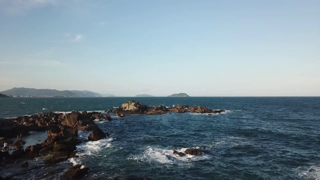 Aerial footage of the the beautifu rocks and sunny beach of Armação in Florianópolis Brazil