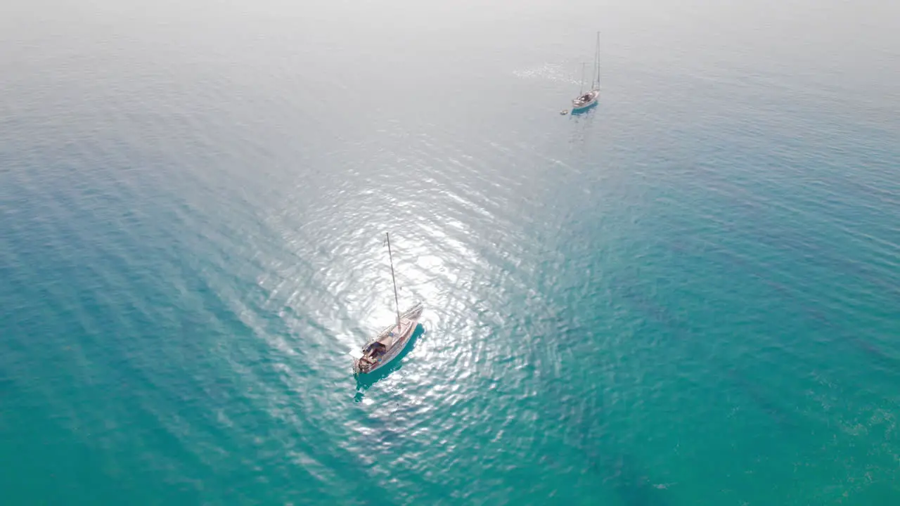 Two small sail boats floating on turqoise blue water