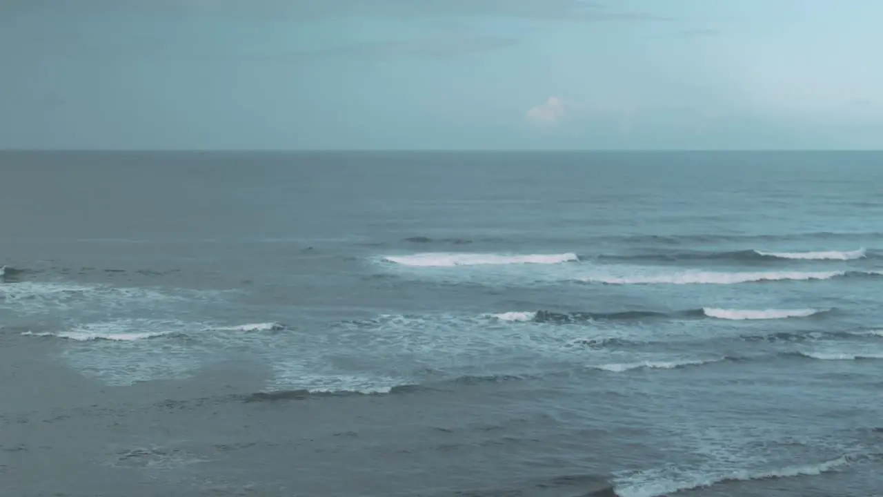 Surfer paddle out through waves on a cold day Extreme Wide Shot