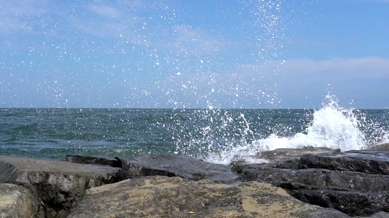 Slow motion video of The waves from the ocean breaking over the rocks on the shore