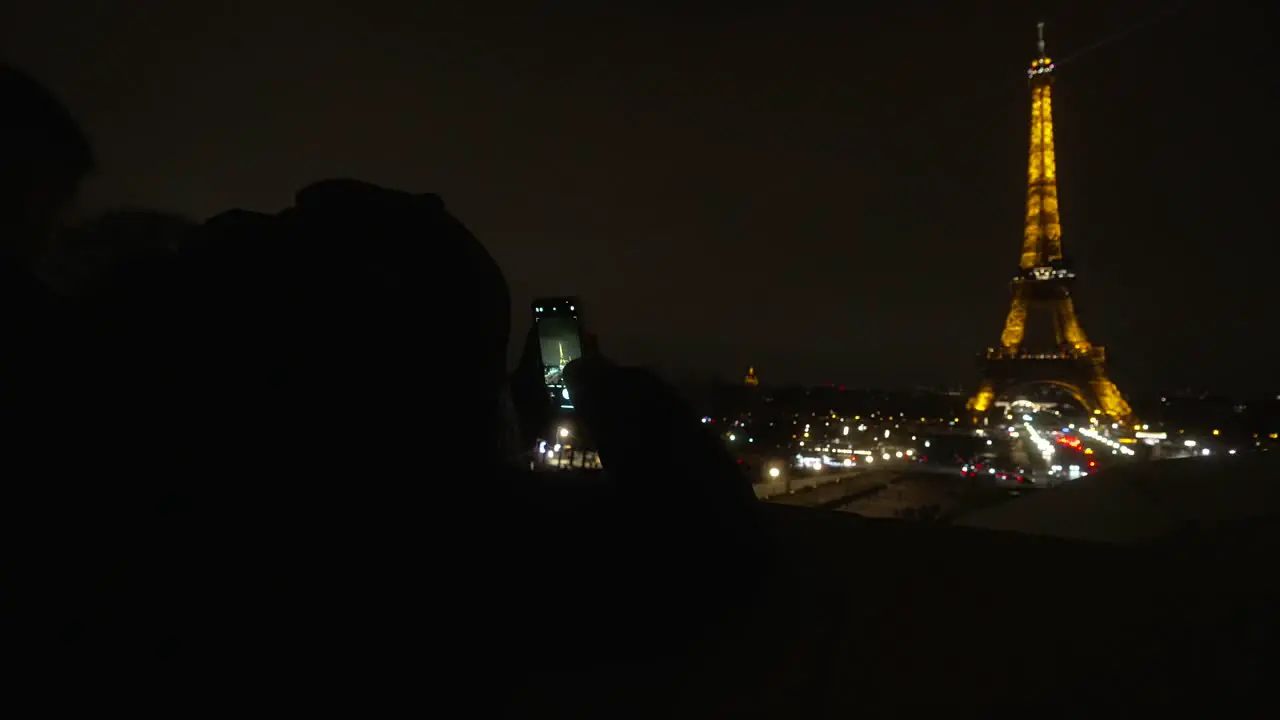 Person taking a photo of the Eiffel Tower with the cell phone in the middle of the night