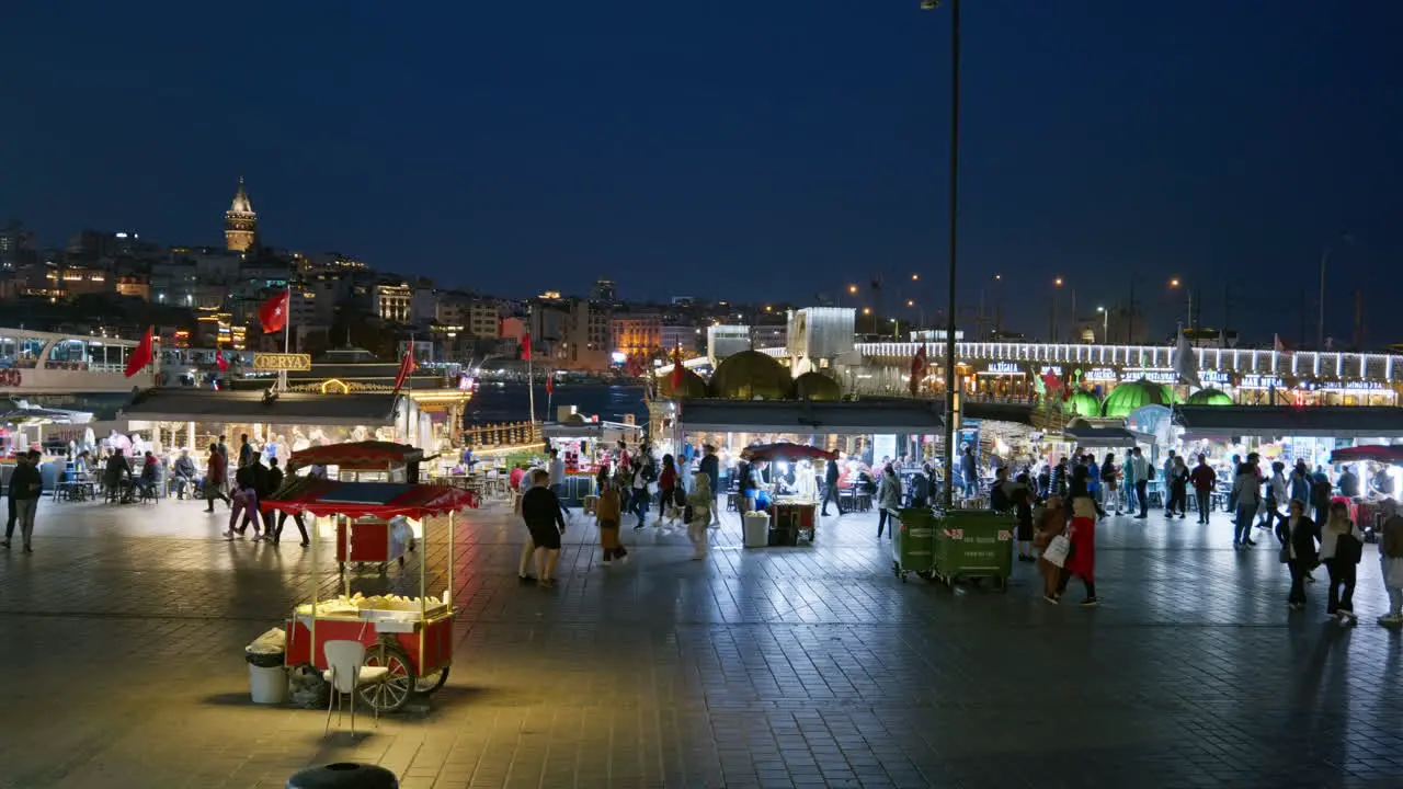 Busy city night scene at Eminonu Pier with illuminated Galata Tower