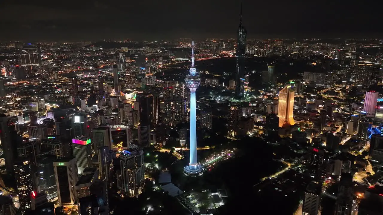 Aerial night drone shot of the Kuala Lumpur Tower in the middke of the city