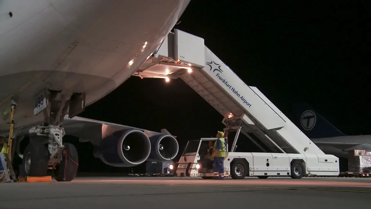 Nighttime airport scene with cargo loading on an airplane via an illuminated airstair