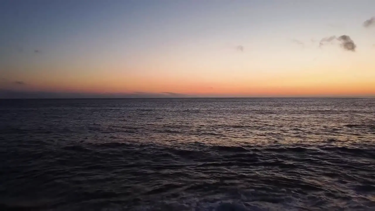 Drone shot flying away from the water towards the beach during sunset