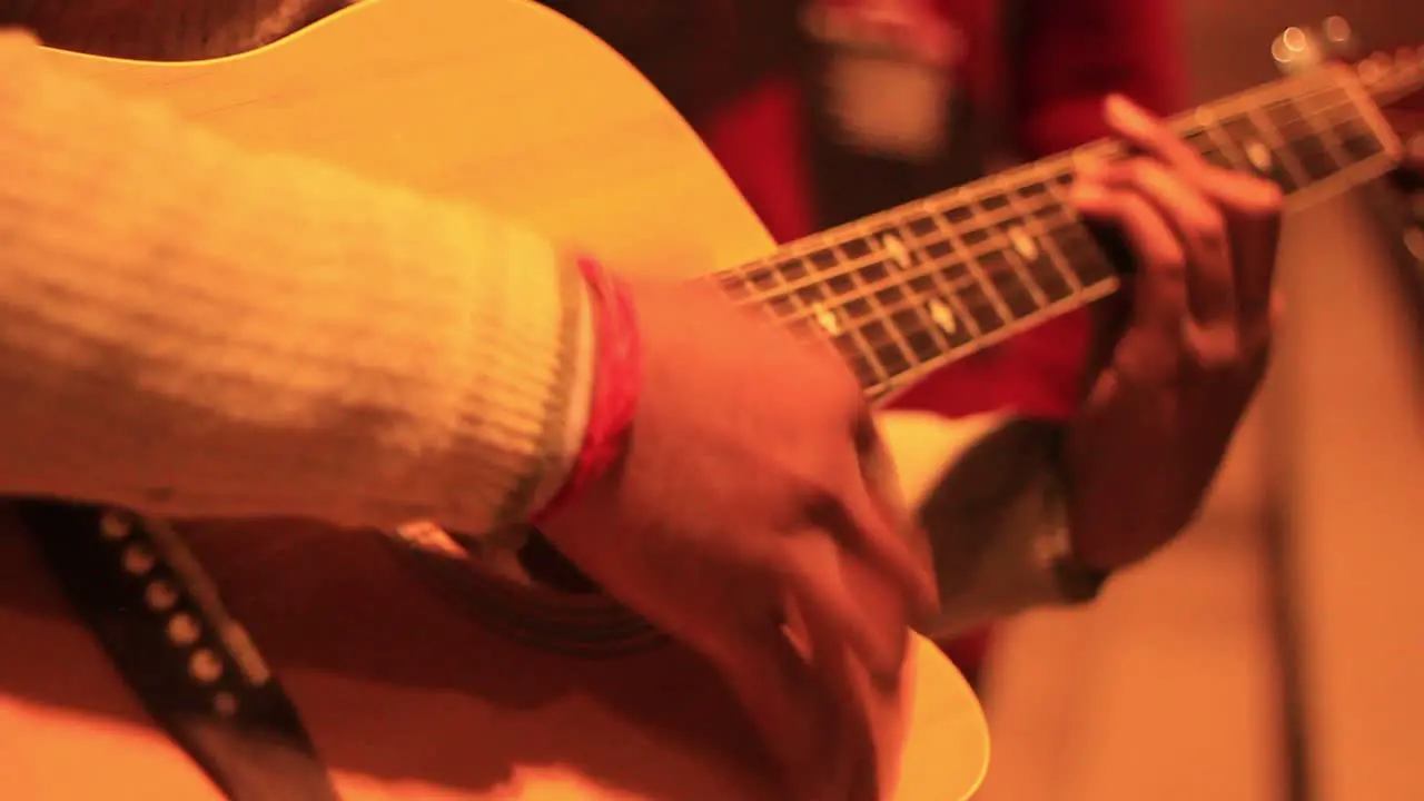 Extreme Closeup steady shot of a human playing a guitar under the streetlight in the night on a ghat in Varanasi with camera movement