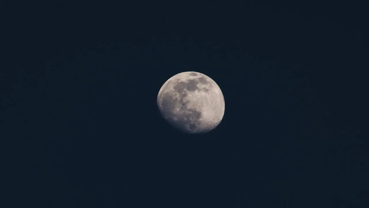 Full moon slowly moving across a dark blue sky at night telescope video