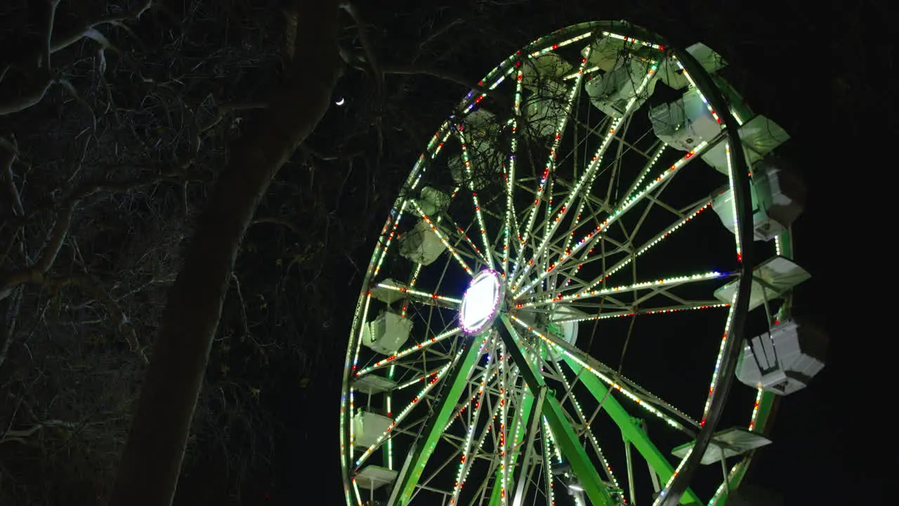 A low angle Wide shot of a Ferris wheel spinning and making a revolution in the night