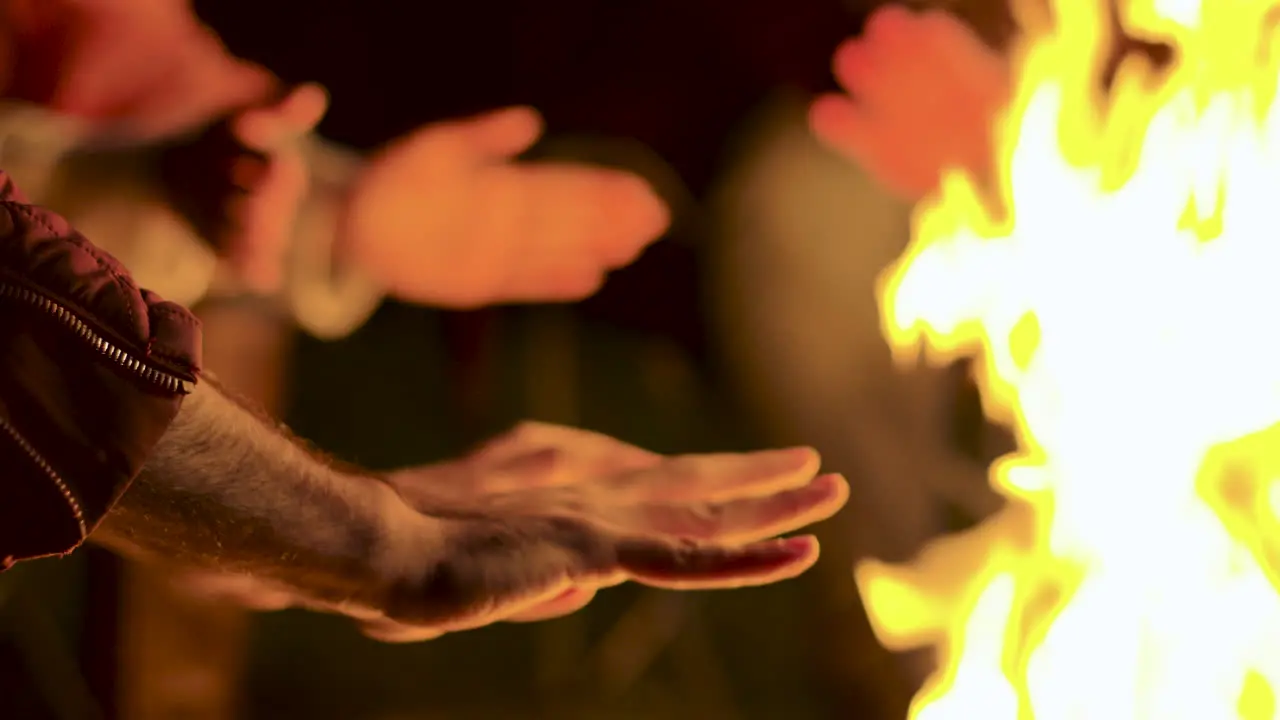 Close up of man warming up his hands at camp fire