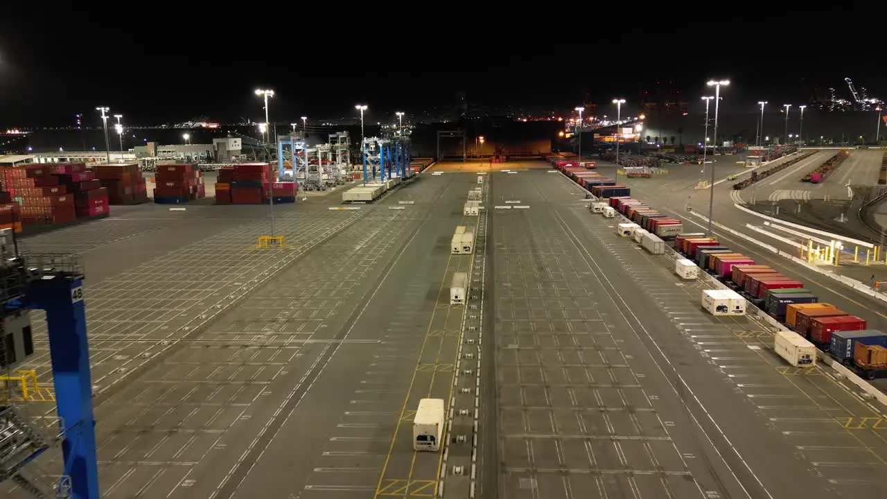 drone view of Long Beach shipyard at night showcasing towering cranes and rows of cargo containers