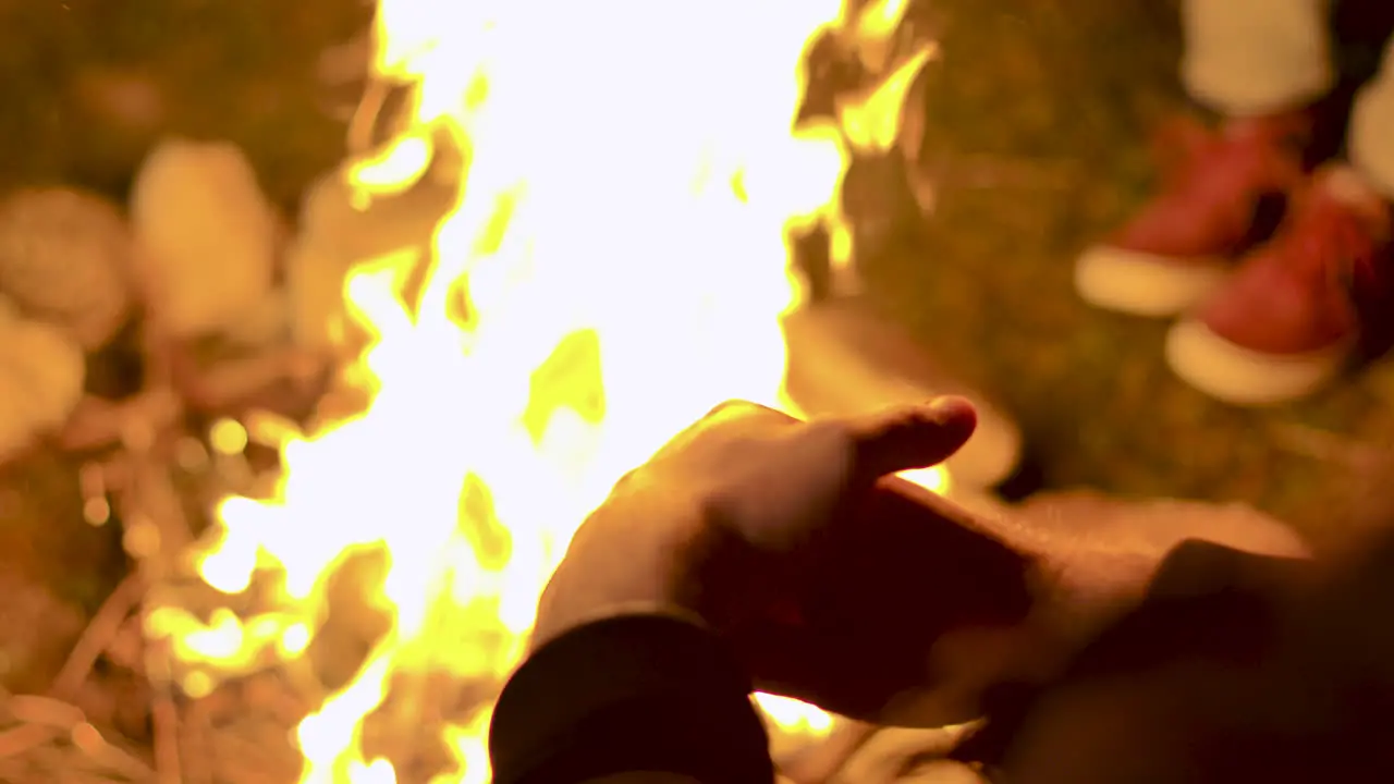 Close up of tourist sitting near the camp fire at night