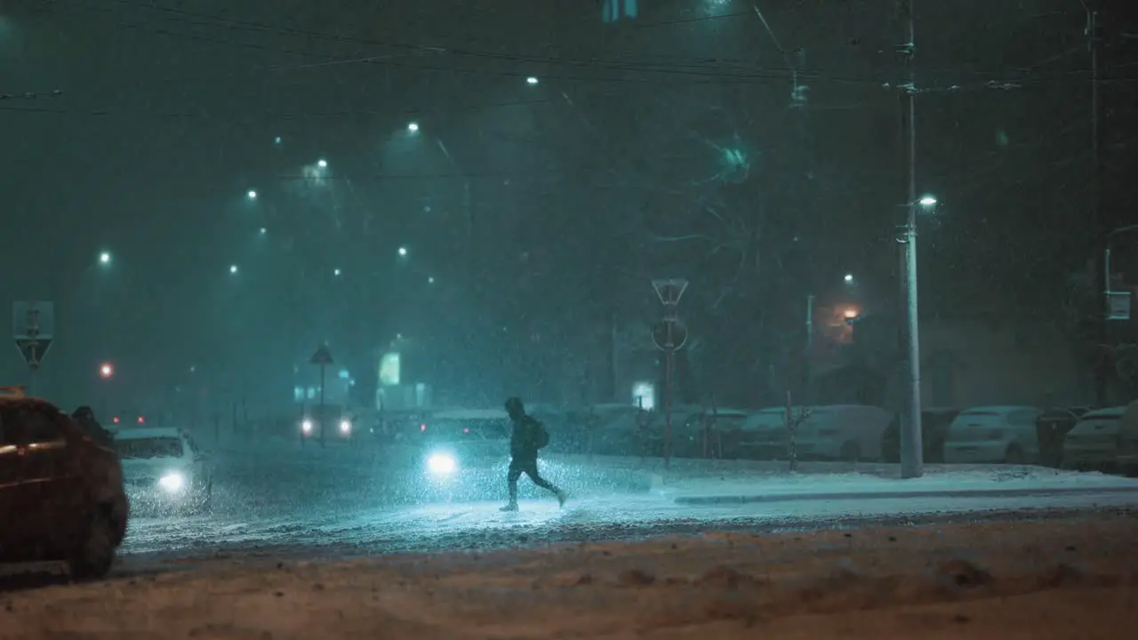 People silhouettes crossing the street cars driving on a frosty winter night during a blizzard