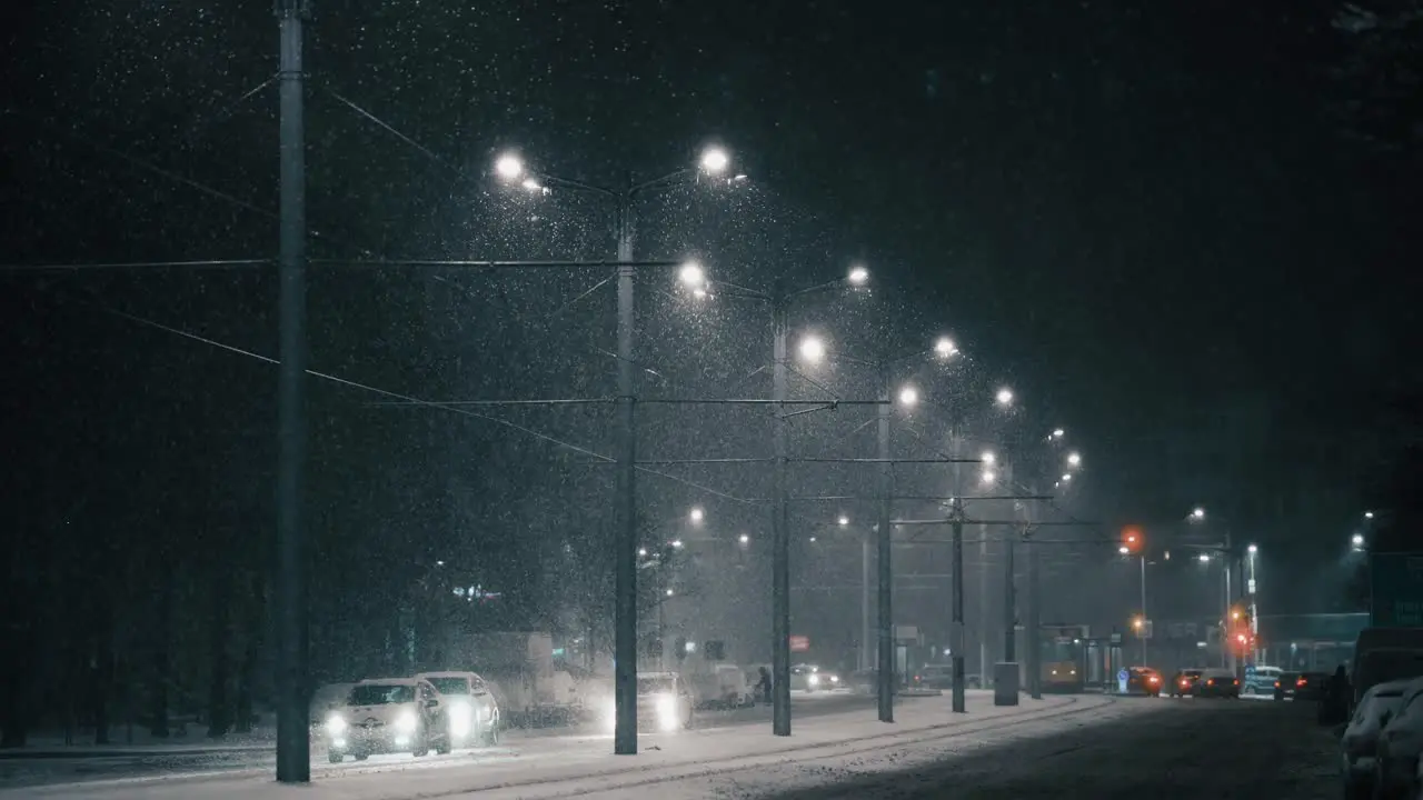 Cars driving in the city on a frosty winter night during a blizzard