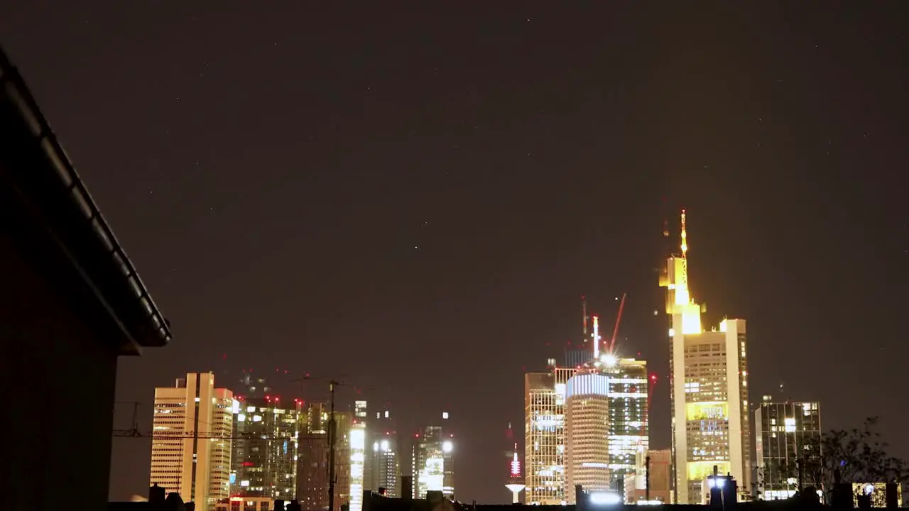 Nighttime view of Frankfurt skyline with illuminated buildings under a starry sky timelapse